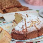 Close-up of a homemade sponge cake topped with powdered sugar on a table.