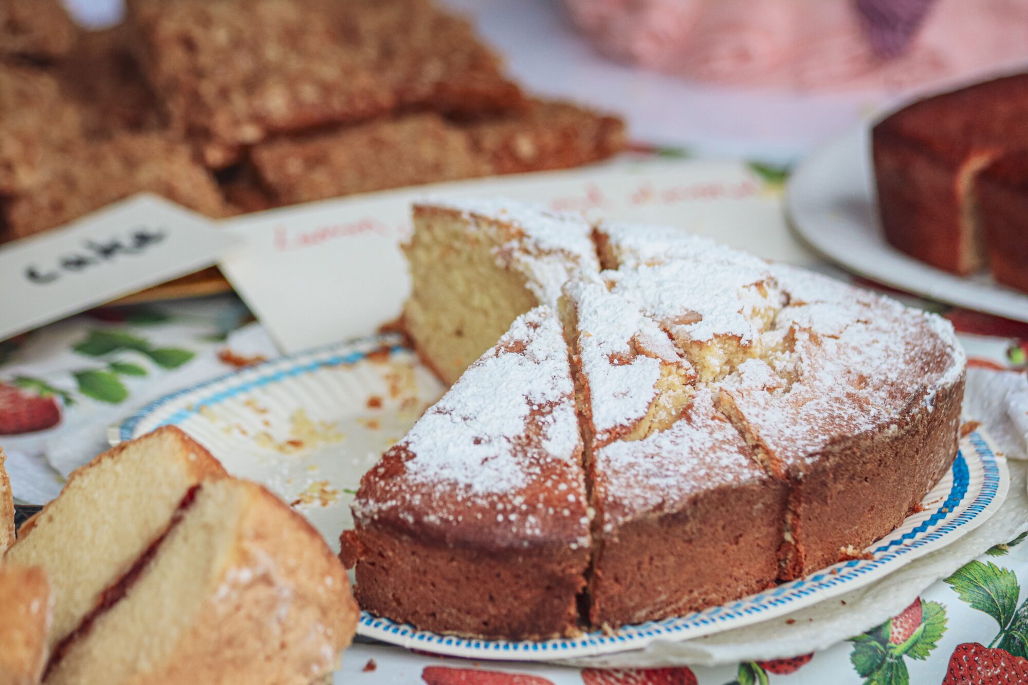 Close-up of a homemade sponge cake topped with powdered sugar on a table.