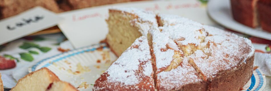 Close-up of a homemade sponge cake topped with powdered sugar on a table.