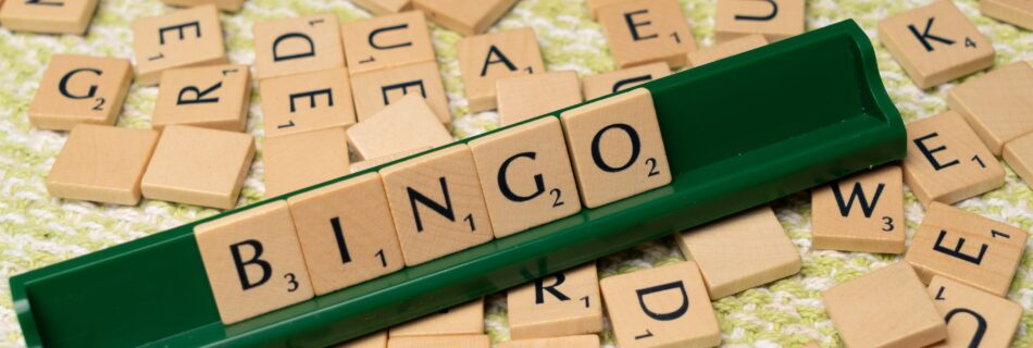 Wooden Scrabble tiles arranged to spell 'BINGO' on a green rack.
